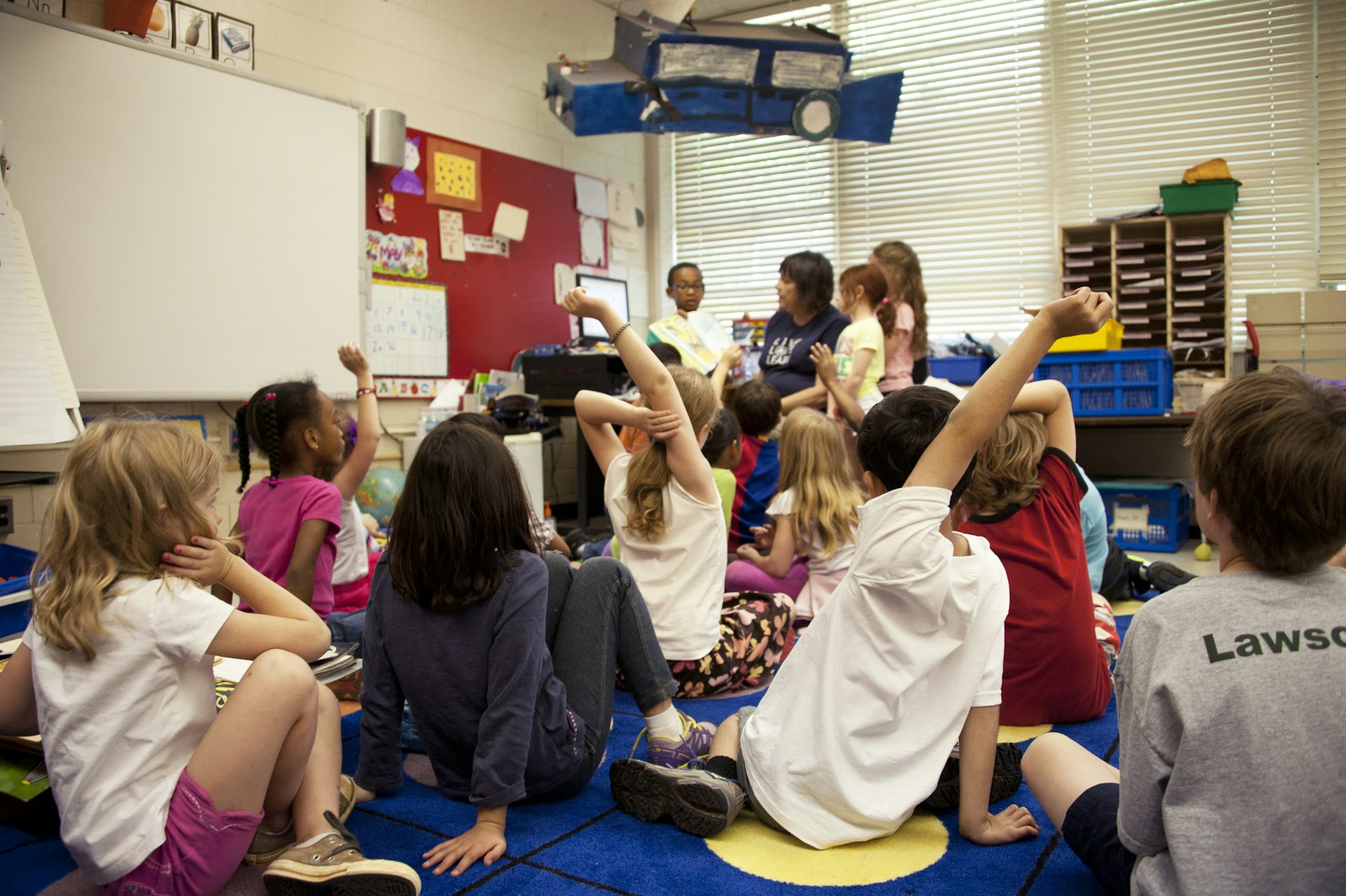 Young students raising their hands in an elementary school classroom